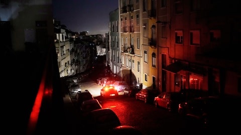 Ein Auto fährt während eines landesweiten Stromausfalls eine unbeleuchtete Straße in Lissabon entlang.