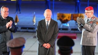 Der scheidende Bundeskanzler Olaf Scholz (M, SPD) lächelt, während Verteidigungsminister Boris Pistorius (l, SPD) und General Carsten Breuer, Generalinspekteur der Bundeswehr, applaudieren, beim großen Zapfenstreich der Bundeswehr anlässlich seiner Verabschiedung.
