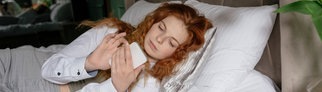 Eine Frau liegt im Bett und guckt auf ein Handy
