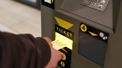 Person zahlt an Parkautomat im Parkhaus