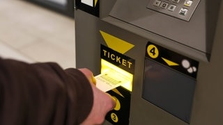 Person zahlt an Parkautomat im Parkhaus