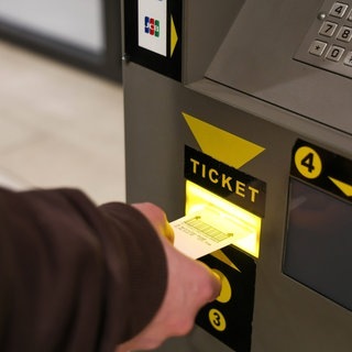 Person zahlt an Parkautomat im Parkhaus