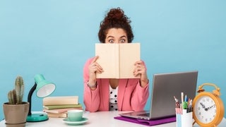 Eine Frau sitzt am Schreibtisch und schaut geschockt über ihren Kalender. Ein Verband will Feiertage streichen.