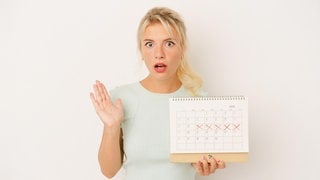 Eine Frau hält geschockt einen Kalender in der Hand. Ein Verband will Feiertage streichen.