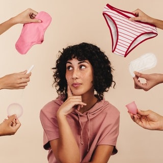 Eine Frau schaut nachdenklich zur Seite, viele Hände halten ihr Produkte für die Periode hin. Menstruation ist noch immer ein Tabuthema.