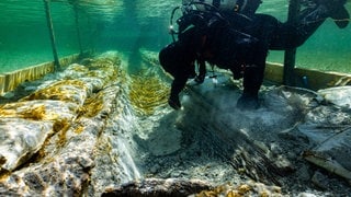 2019: Huber fotografiert einen Kollegen, der im Bodensee am Fund eines rund 4.000 Jahre alten Einbaums arbeitet. Das Team erhofft sich neue Erkenntnisse über die Geschichte des Ur-Bootes und vielleicht sogar des Lebens an dem Gewässer in der Steinzeit und frühen Bronzezeit. (Foto: dpa Bildfunk, picture alliance/dpa/Wirtschaftsministerium | Florian Huber) 2019: Huber fotografiert einen Kollegen, der im Bodensee am Fund eines rund 4.000 Jahre alten Einbaums arbeitet. Das Team erhofft sich neue Erkenntnisse über die Geschichte des Ur-Bootes und vielleicht sogar des Lebens an dem Gewässer in der Steinzeit und frühen Bronzezeit.