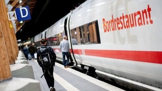 Fahrgäste gehen am frühen Morgen mit ihrem Gepäck über einen Bahnsteig