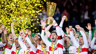 VfB Stuttgart gewinnt den DFB-Pokal gegen Arminia Bielefeld: Spieler reißen den Pokal in die Höhe - die Fans im Ausnahmezustand.