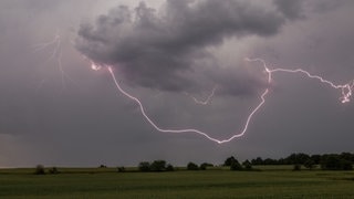 Der Blitz eines Gewitters ist am Nachmittag über einem Feld bei Oberursel-Oberstedten zu sehen