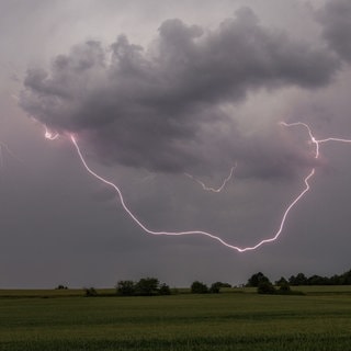 Der Blitz eines Gewitters ist über einem Feld bei Oberursel-Oberstedten zu sehen. Für Mittwoch hat der Deutsche Wetterdienst heftige Unwetter im Süden Deutschlands angekündigt mit Gewitter, Hagel und Starkregen.