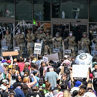 Menschen protestieren in Los Angeles gegen die Migrationspolitik von Trump. Die Nationalgarde der USA steht ihnen gegenüber.