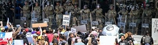 Menschen protestieren in Los Angeles gegen die Migrationspolitik von Trump. Die Nationalgarde der USA steht ihnen gegenüber.