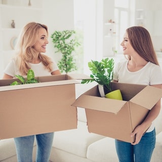 Eine Mutter und ihre Tocher halten Umzugskartons in der Hand. Im Schnitt ziehen die Deutschen mit 24 Jahren von zu Hause aus.