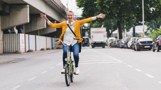 Eine Frau fährt freihändig Fahrrad. Darf ich das laut Regeln der Straßenverkehrsordnung oder riskiere ich ein Bußgeld?