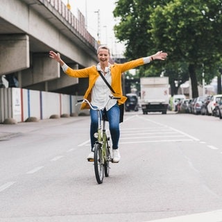 Eine Frau fährt freihändig Fahrrad. Darf ich das laut Regeln der Straßenverkehrsordnung oder riskiere ich ein Bußgeld?