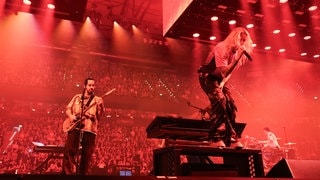Linkin Park auf Deutschland Tour: Mike Shinoda spielt links auf dem Bild Gitarre und Sängerin Emily Armstrong singt bei einem Konzert in der Barclays Arena in Hamburg im September 2024.