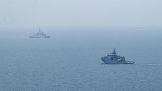 Man sieht zwei französische Marineschiffe vor der Mittelmeerküste.