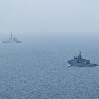 Man sieht zwei französische Marineschiffe vor der Mittelmeerküste.