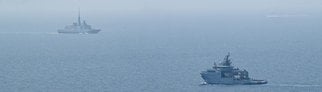 Man sieht zwei französische Marineschiffe vor der Mittelmeerküste.