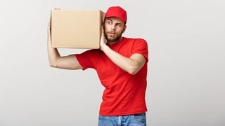 Ein Mann trägt neugierig ein Paket auf dem Arm. Symbolbild für eine Mystery Box.