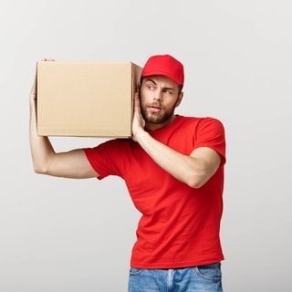 Ein Mann trägt neugierig ein Paket auf dem Arm. Symbolbild für eine Mystery Box.