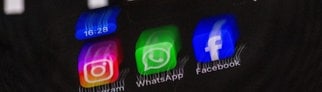 Die Apps Instagram, Facebook und WhatsApp sind auf dem Display eines Smartphones vor dem Logo des Internetkonzerns Meta zu sehen. Meta plant die Einführung von Werbung bei WhatsApp.