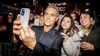 Robbie Williams macht bei der Premiere seines Films „Better Man“ ein Selfie mit Fans