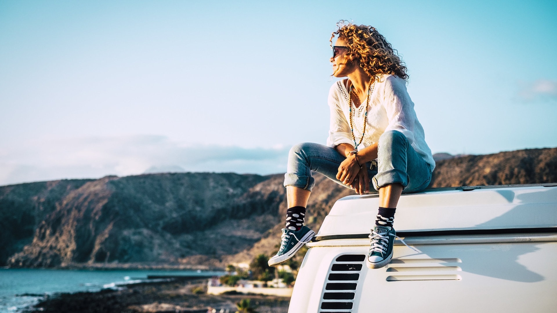 Foto: Adobe Stock/Simona Junge Frau sitzt auf dem Dach des Wohnmobils und schaut in die Landschaft (Foto: Adobe Stock/Simona)