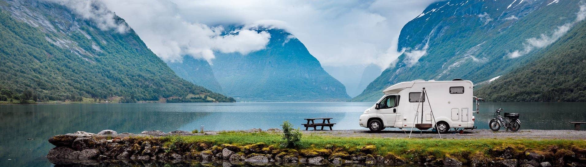 Wohnmobil vor Berg-Panorama an einem See (Foto: Adobe Stock/Gowtham)