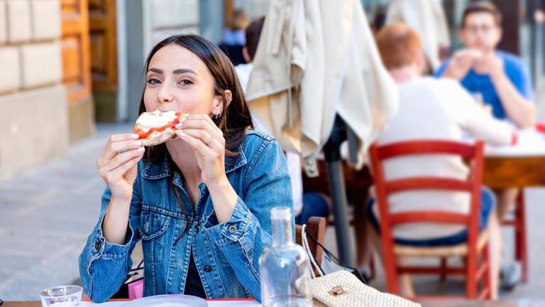 Eine Frau isst Pizza in Italien. (Foto: IMAGO, IMAGO / Westend61)