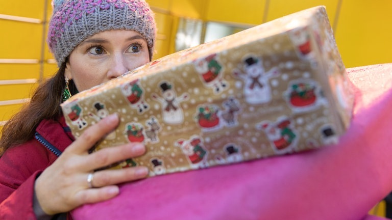 Eine Frau trägt ein paar Geschenke auf ihren Händen (Foto: dpa Bildfunk, Picture Alliance)