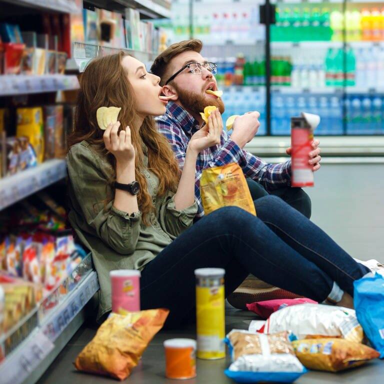 Mann und Frau naschen im Supermarkt (Foto: AdobeStock)