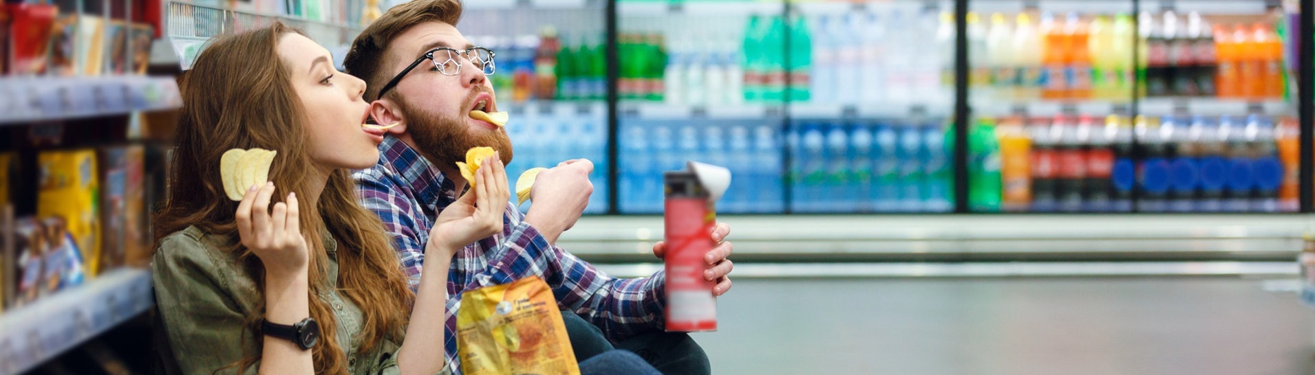 Mann und Frau naschen im Supermarkt (Foto: AdobeStock)