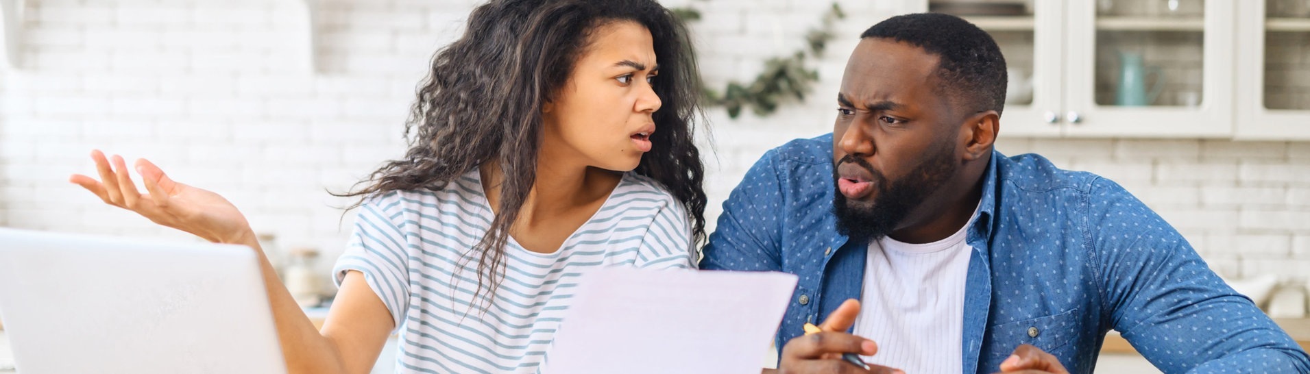 Ein Mann und eine Frau sitzen am Küchentisch und sind entsetzt von einer Rechnung. (Foto: Adobe Stock, Vadim Pastuh)