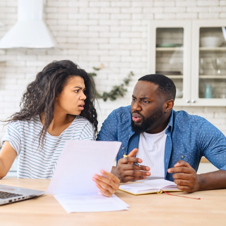 Ein Mann und eine Frau sitzen am Küchentisch und sind entsetzt von einer Rechnung. (Foto: Adobe Stock, Vadim Pastuh)