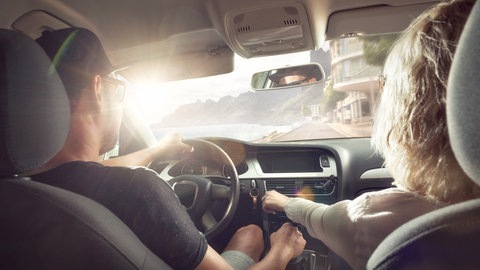 Urlaubsstimmung: Ein paar sitzt in einem Auto und fährt der Sonne entgegen (Foto: Adobe Stock, photoschmidt)