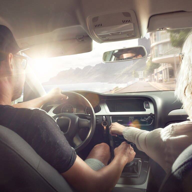 Urlaubsstimmung: Ein paar sitzt in einem Auto und fährt der Sonne entgegen (Foto: Adobe Stock, photoschmidt)