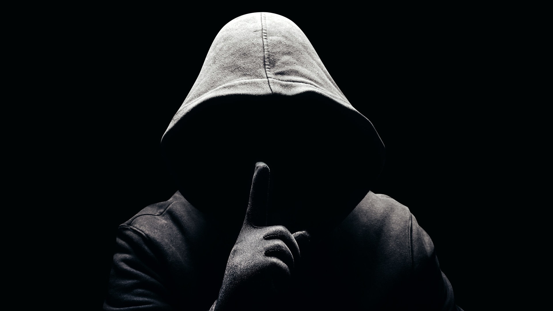 Eine dunkle Person, ohne Gesicht hält den Finger als Aufforderung zur Verschwiegenheit vor den Mund (Foto: Adobe Stock, breakermaximus)