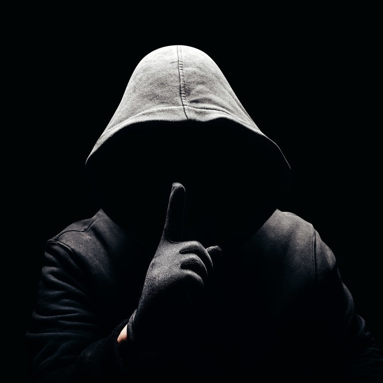 Eine dunkle Person, ohne Gesicht hält den Finger als Aufforderung zur Verschwiegenheit vor den Mund (Foto: Adobe Stock, breakermaximus)