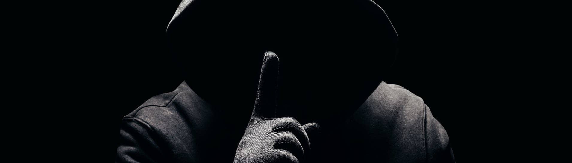 Eine dunkle Person, ohne Gesicht hält den Finger als Aufforderung zur Verschwiegenheit vor den Mund (Foto: Adobe Stock, breakermaximus)