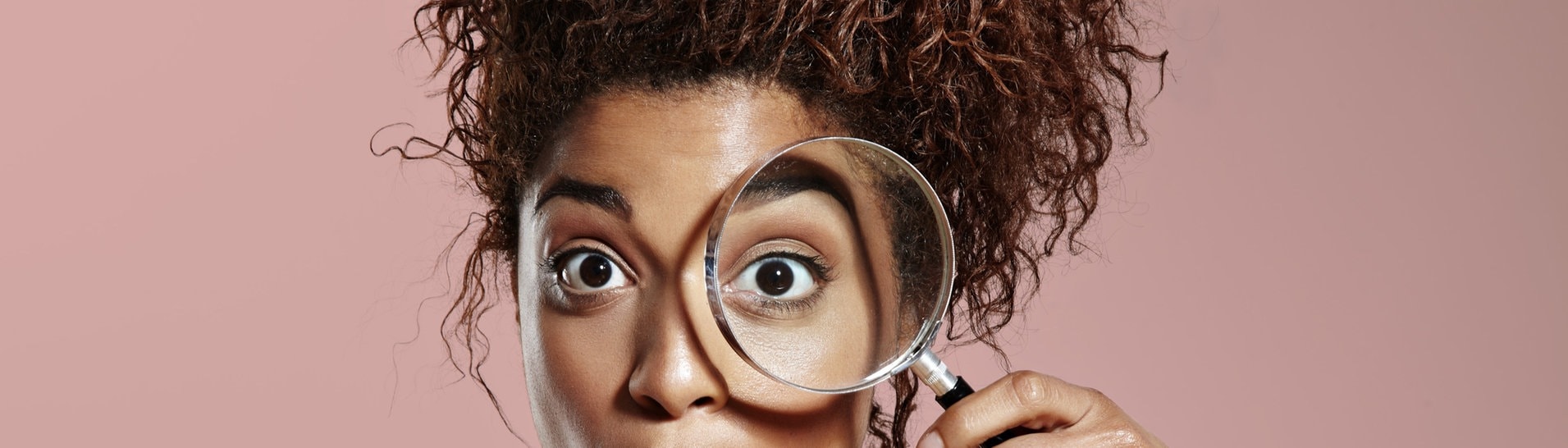 Überraschte Frau schaut durch eine Lupe. (Foto: Adobe Stock, Anastasia)