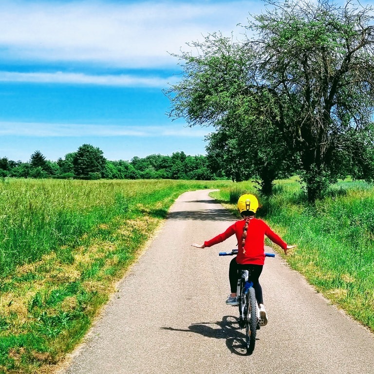 Ein Kind auf einem Fahrrad fährt auf einem Feldweg bei gutem Wetter (Foto: Stefan Scheurer)