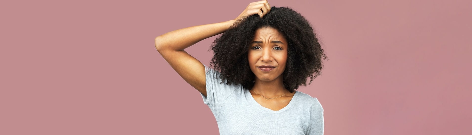 Junge Frau greift sich in ihre Haare und grübelt über unser Rechtschreib-Quiz (Foto: IMAGO, IMAGO / Zoonar)