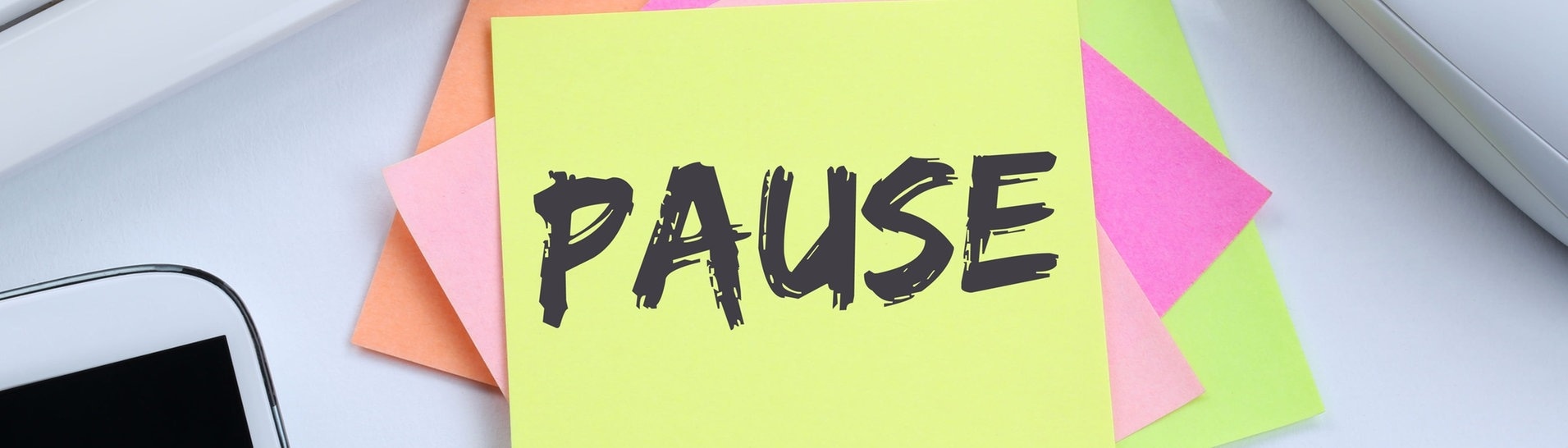 Notiz-Zettel mit der Aufschrift Pause erinnert daran, dass Zeit ist für eine Unterbrechung der Arbeit. Der Schreibtisch sieht nach Büro aus mit Tastatur, Smartphone und Maus. (Foto: Adobe Stock, Markus Mainka)