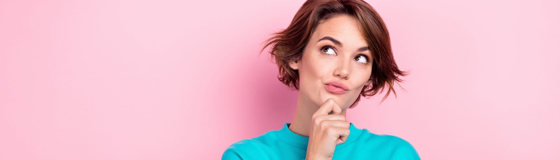 Junge Frau hält sich das Kinn und sieht nachdenklich aus – vielleicht grübelt sie über deutsche Rechtschreibung und Grammatik und sucht nach Eselsbrücken, um sie sich zu merken. (Foto: Adobe Stock, deagreez)
