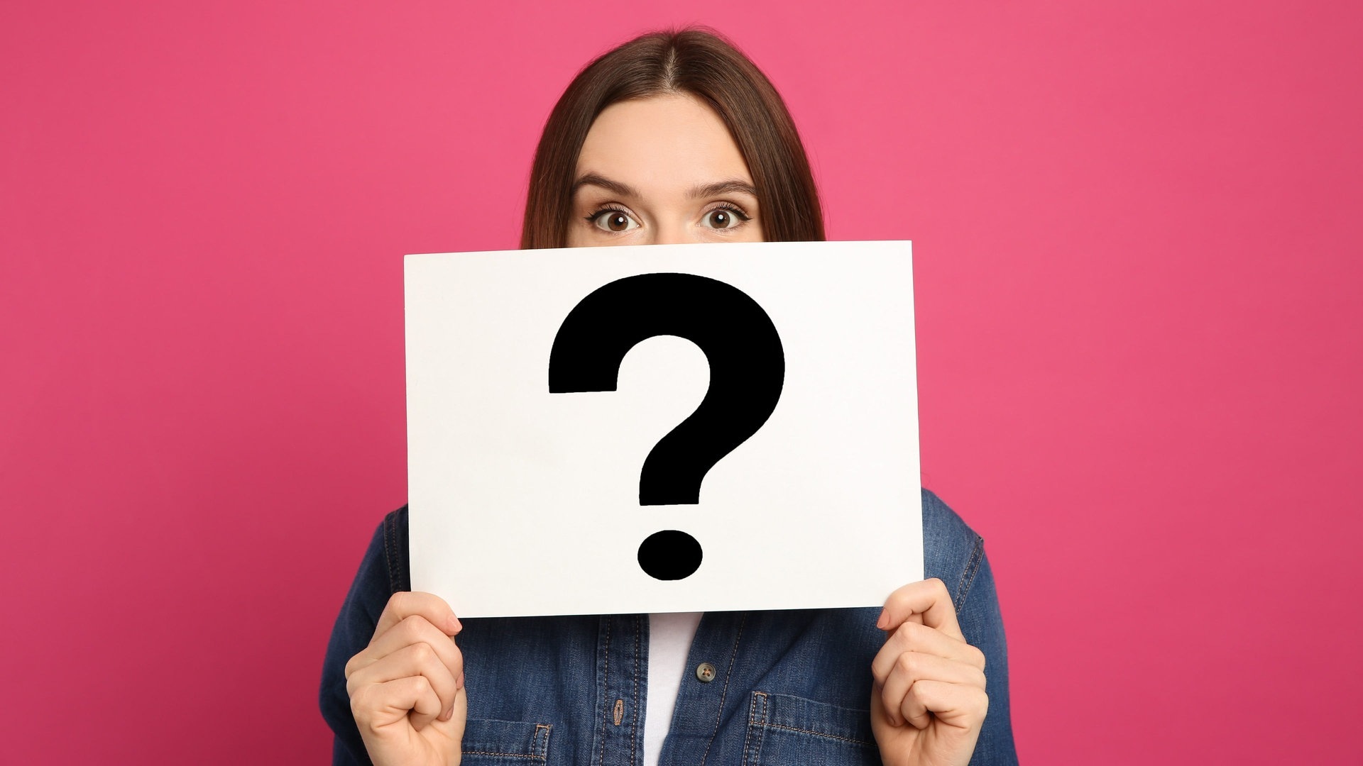 Junge Frau hält sich ein Schild vors Gesicht, auf dem ein Fragezeichen abgedruckt ist – vielleicht kommt sie beim Quiz zu Vergangenheitsformen nicht weiter. (Foto: Adobe Stock, New Africa)