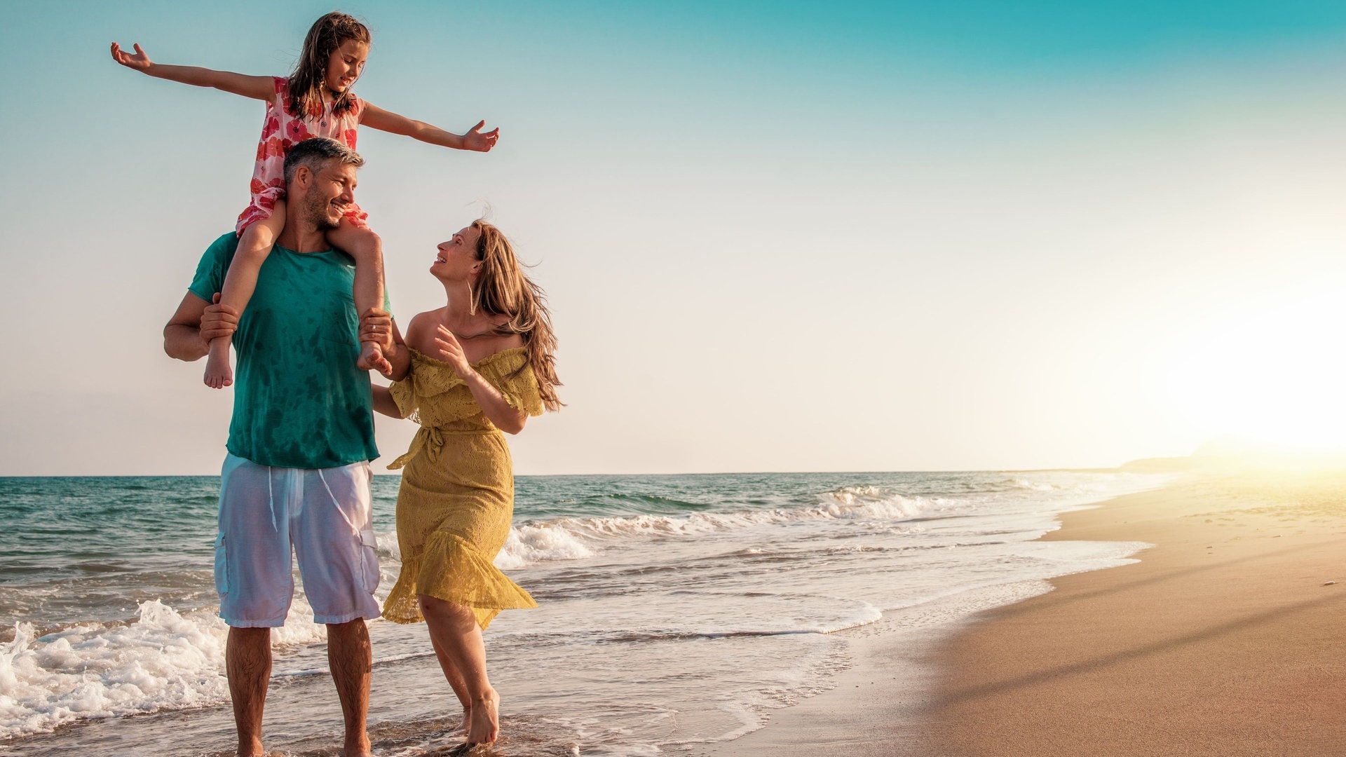 Foto: Adobe Stock, detailblick-foto Eine junge Familie spaziert am Strand. Mann, Frau und ein Kind auf den Schultern des Vaters im Urlaub. Es drohen keine Konsequenzen und es ist keine Arbeitsverweigerung, wenn sie sich von hier aus nicht zurück zur Arbeit holen lassen. (Foto: Adobe Stock, detailblick-foto)