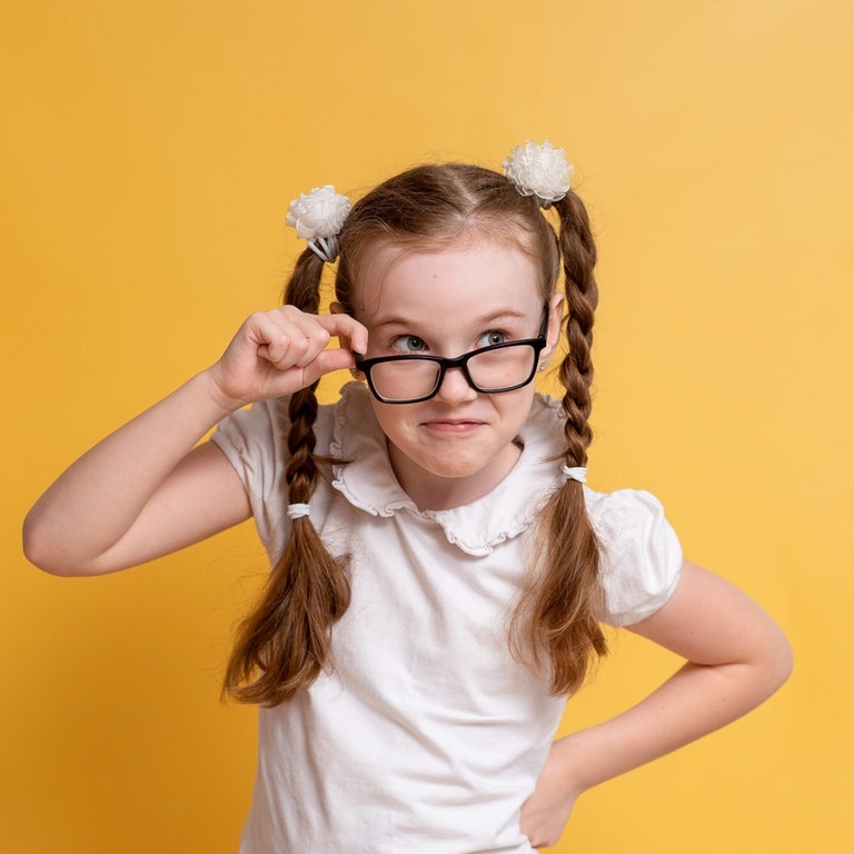 Mädchen mit Zöpfen und einer Brille sieht sehr schlau aus. Sie kennt sich vermutlich alle Eselsbrücken und Merksätze für die deutsche Rechtschreibung. (Foto: Adobe Stock, Katrin_Primak)