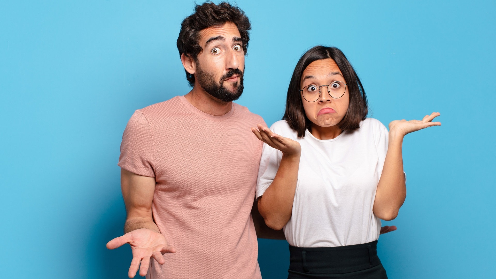 Junges Paar steht nebeneinander mit einem fragenden Gesichtsausdruck. Sie zuckt mit den Schultern und hält die Arme hoch. Vermutlich scheitern sie gerade beide am Quiz mit der Frage, welche Wörter zusammen und welche getrennt geschrieben werden. (Foto: Adobe Stock, kues1)