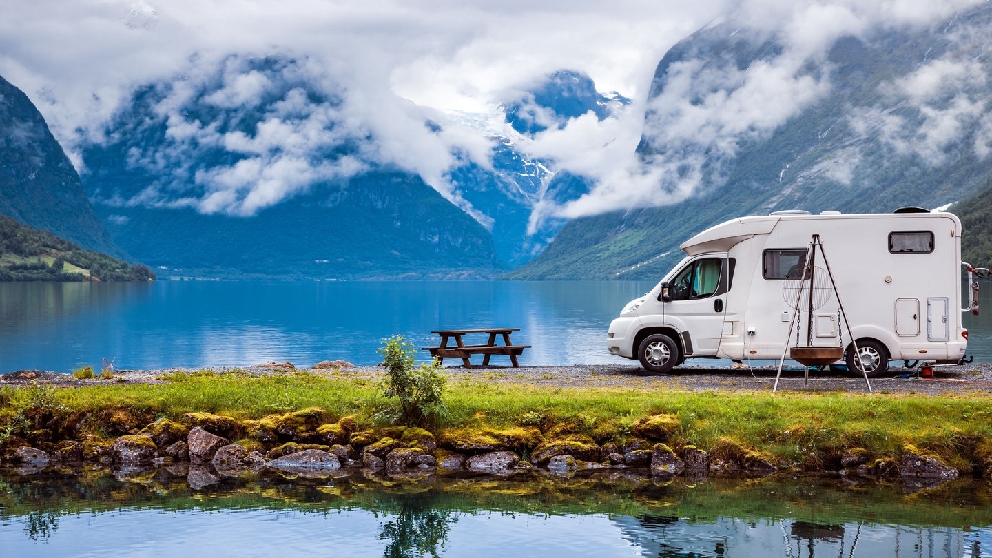 Wohnmobil vor Berg-Panorama an einem See (Foto: Adobe Stock/Gowtham)